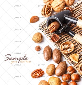 عکس با کیفیت آجیل های خوشمزه در کنار فندوق شکن و تعدادی آجیل شکسته شده در کنار آن