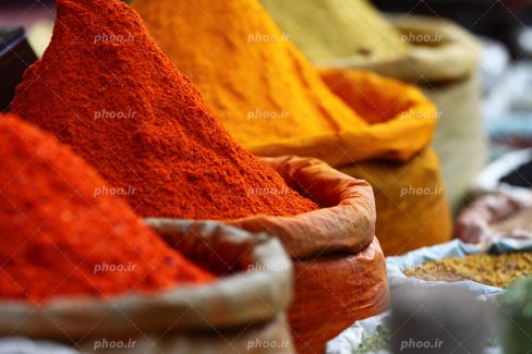 عکس با کیفیت زرد چوبه و پودر فلفل قرمز و ادویه جات خوش رنگ داخل کیسه های کاغذی در کنار یکدیگر