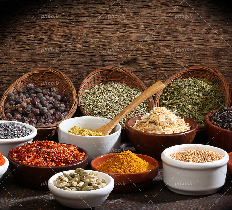 عکس با کیفیت هل و زعفران و انجیر خشک شده و چند گیاه دارویی دیگر در ظرف های سفید چینی و سبد های حصیری در کنار یکدیگر