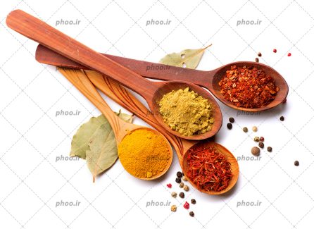 عکس با کیفیت زرد چوبه و زعفران و پودر زنجبیل در قاشق های چوبی و در اطراف آن برگ بو و دانه های فلفل سفید و قرمز ریخته شده است