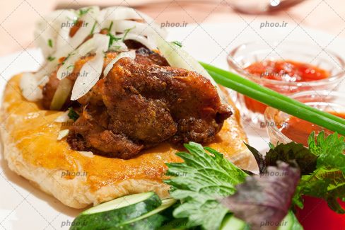 عکس با کیفیت چلوگوشت بر روی یک تکه نان در کنار سبزیجات از نمای نزدیک