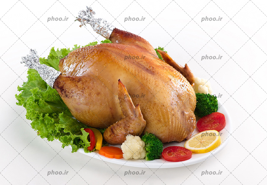 عکس با کیفیت مرغ بریان تزئین شده با لیمو و گوجه و کلم بروکلی و کاهو و هویچ در ظرف چینی سفید