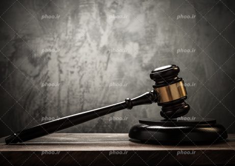 عکس با کیفیت چکش عدالت به رنگ مشکی بر روی میز و بکگراند به رنگ خاکستری