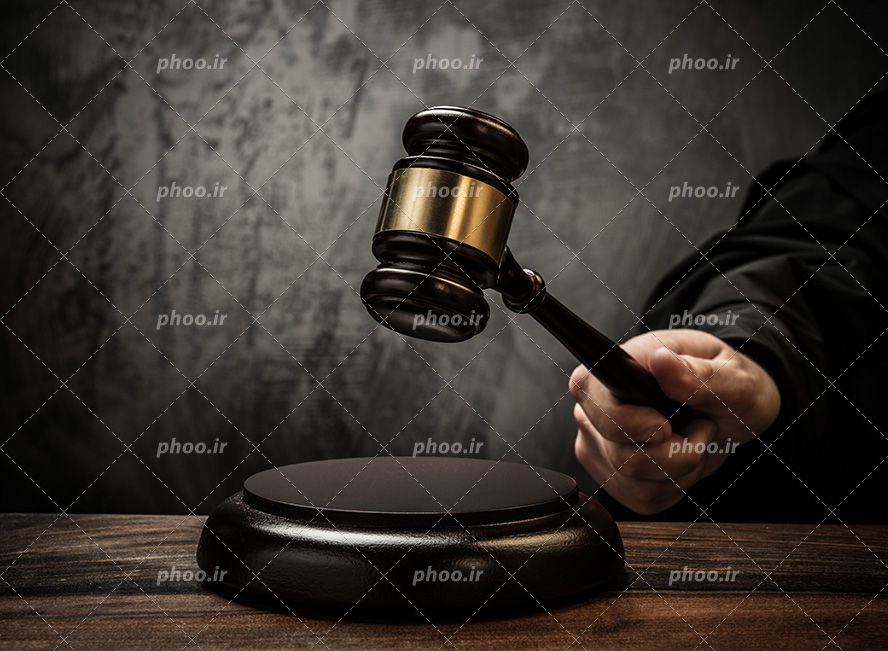 عکس با کیفیت قاضی در حال زدن چکش عدالت و پس زمینه حاکستری