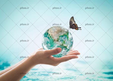 عکس با کیفیت کره زمین از جنس آب در دست زن و پروانه ای زیبا نشسته بر روی کره زمین