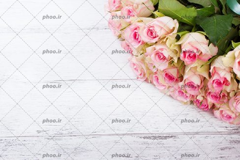 عکس با کیفیت دسته گل های رز به رنگ صورتیبر روی میز چوبی