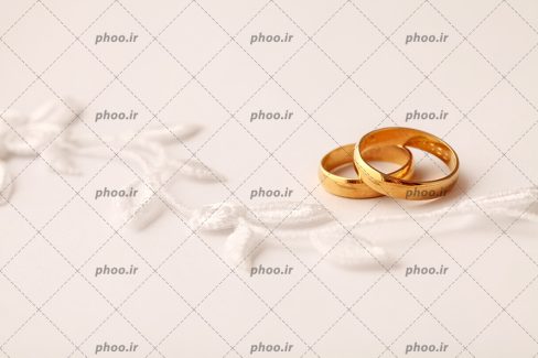 عکس با کیفیت پارچه گلدوزی شده و دو حلقه طلایی در کنار گل های روی پارچه