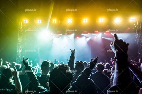 عکس با کیفیت مردم در کنسرت در حال خوشحالی و رقص نور ها به رنگ زرد
