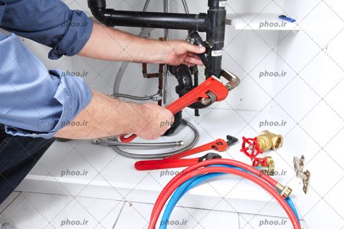 عکس با کیفیت مهندس تاسیسات مکانیکی در حال تعمیرات لوله های آب
