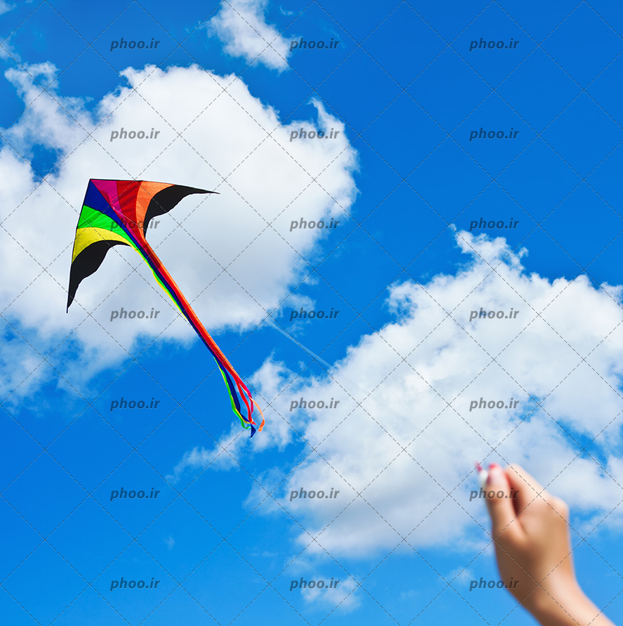 عکس با کیفیت بادبادک زیبا در دست زن و در آسمان آبی در حال پرواز