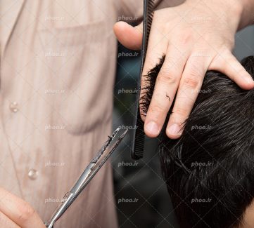 عکس با کیفیت آرایشگر در حال اصلاح موهای مرد از نمای نزدیک