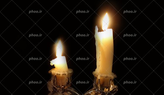 عکس با کیفیت دو شمع داخل شمعدان و پس زمینه به رنگ مشکی