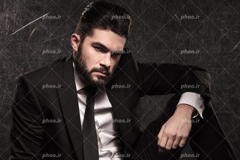 عکس با کیفیت مرد با چهره ی جذاب و با کت و شلوار مشکی و پس زمینه به رنگ مشکی