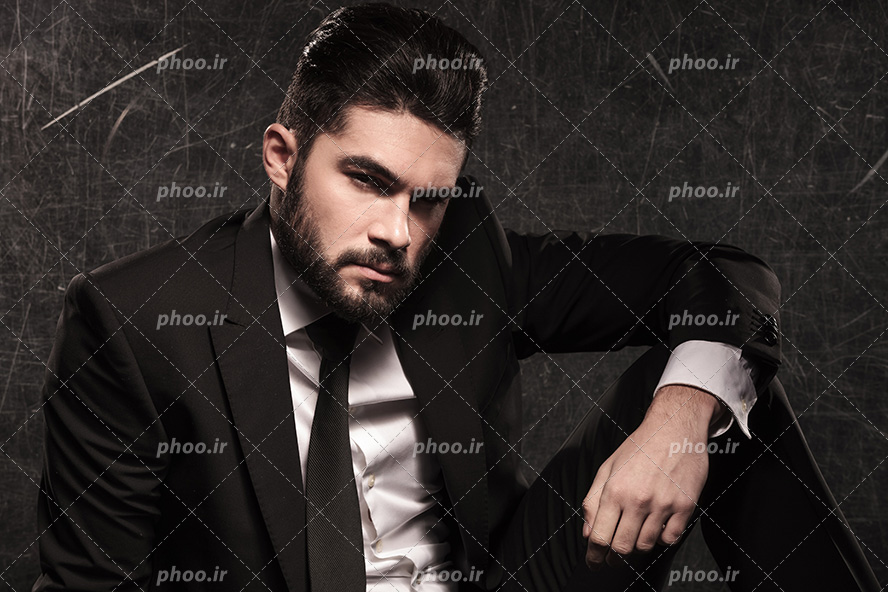 عکس با کیفیت مرد با چهره ی جذاب و با کت و شلوار مشکی و پس زمینه به رنگ مشکی