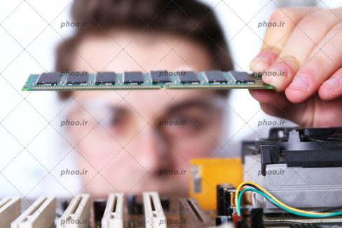 عکس با کیفیت مرد در حال نصب قطعات مادربرد روی آن