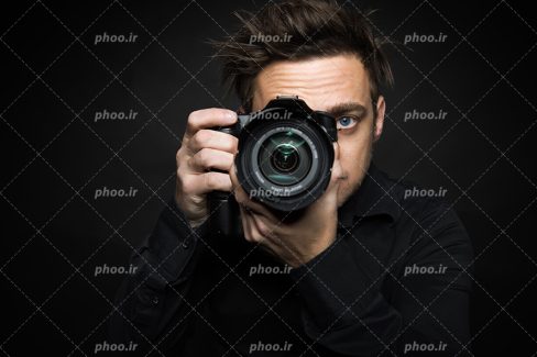 عکس با کیفیت دوربین در دست مرد و در حال عکاسی و پس زمینه به رنگ مشکی