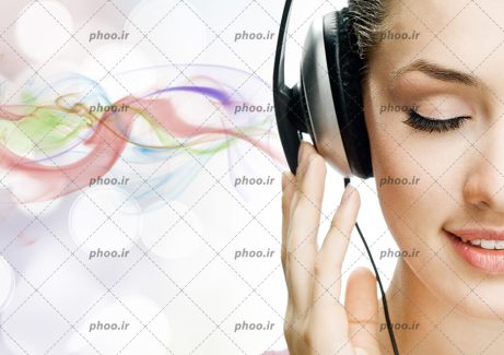 عکس با کیفیت زن در حال گوش دادن به موزیک با هدفون بزرگ و پس زمینه دود های رنگارنگ