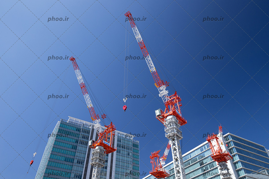 عکس با کیفیت تاور کرین های عظیم سفید و قرمز در کنار ساختمان های شکیل مرتفع