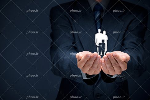 عکس با کیفیت خانواده ای کاغذی در دستان مرد شیک پوش کت شلواری به منظور حفاظت از خانواده