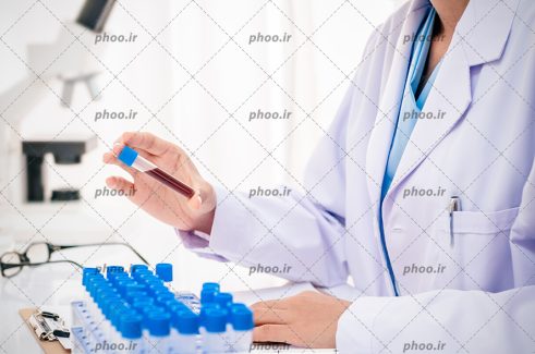 عکس با کیفیت دکتر در حال بررسی نمونه خون های گرفته شده در آزمایشگاه و ثبت آنها