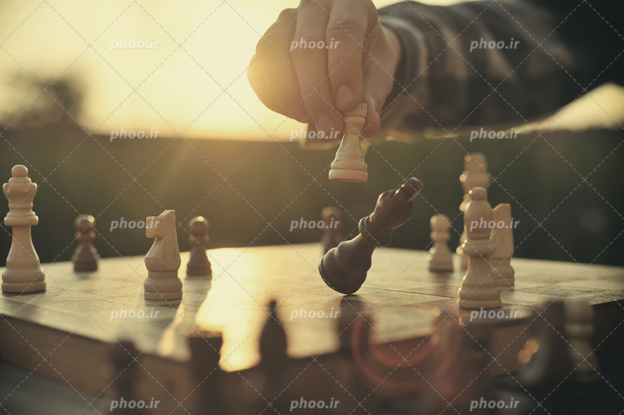 عکس با کیفیت مرد در حال بازی شطرنج و خارج کردن مهره از بازی از نمای نزدیک