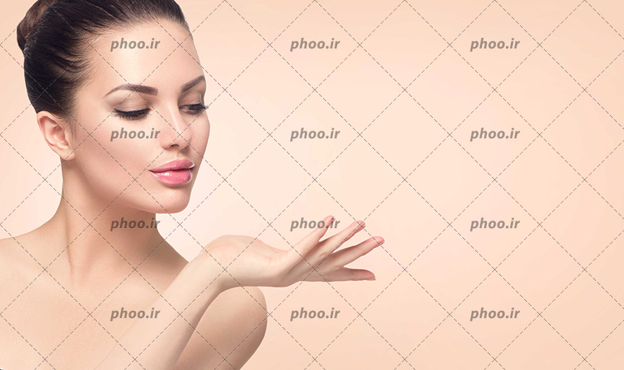 عکس با کیفیت زن با پوست صاف و لطیف و گرفتن دست خود در کنار صورتش و در حال نگاه کردن به دست