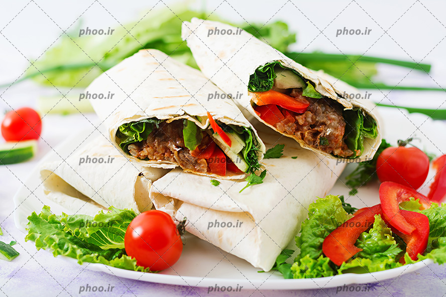 عکس با کیفیت شاورما چیده شده بر روی یکدیگر در ظرف سفید با تزئین سبزیجات