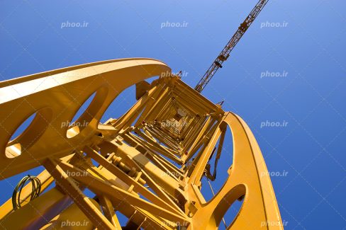 عکس با کیفیت تاورکرین زرد رنگ از نمای پایین و آسمان آبی
