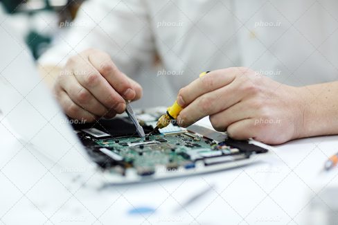 عکس با کیفیت مرد سفید پوش در حال تعمیر برد و قطعات سیستمی با ابزار تعمیرات