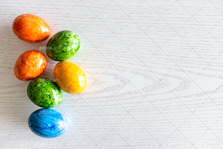 عکس با کیفیت تخم مرغ های نارنجی و سبز و آبی چیده شده در کنار یکدیگر در پس زمینه سفید