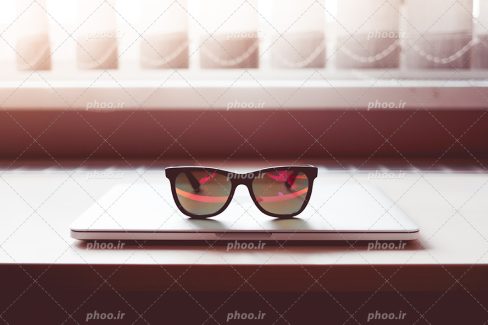 عکس با کیفیت زیبا عینک بسیار زیبا قرار گرفته بر روی میز