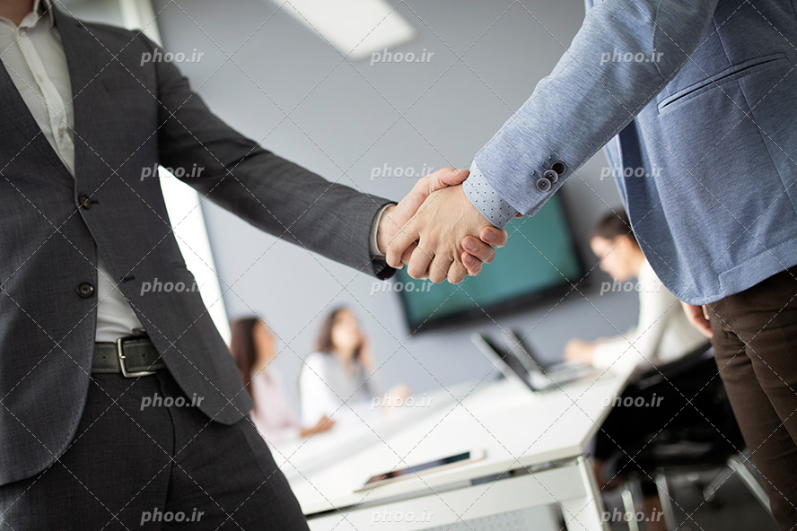 عکس با کیفیت دو مرد با کت و شلوار شیک زیبا در حال دست دادن