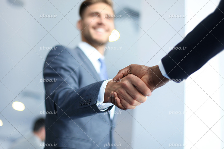 عکس با کیفیت و زیبا مرد با کت و شلوار طوسی در حال دست دادن به همکار خود