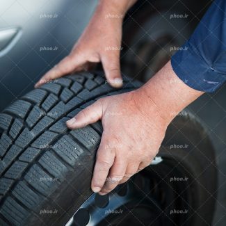 عکس با کیفیت لاستیک در دست مرد تعمیرکار از نمای نزدیک