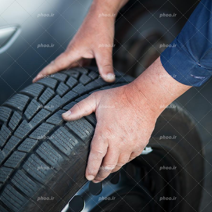 عکس با کیفیت لاستیک در دست مرد تعمیرکار از نمای نزدیک