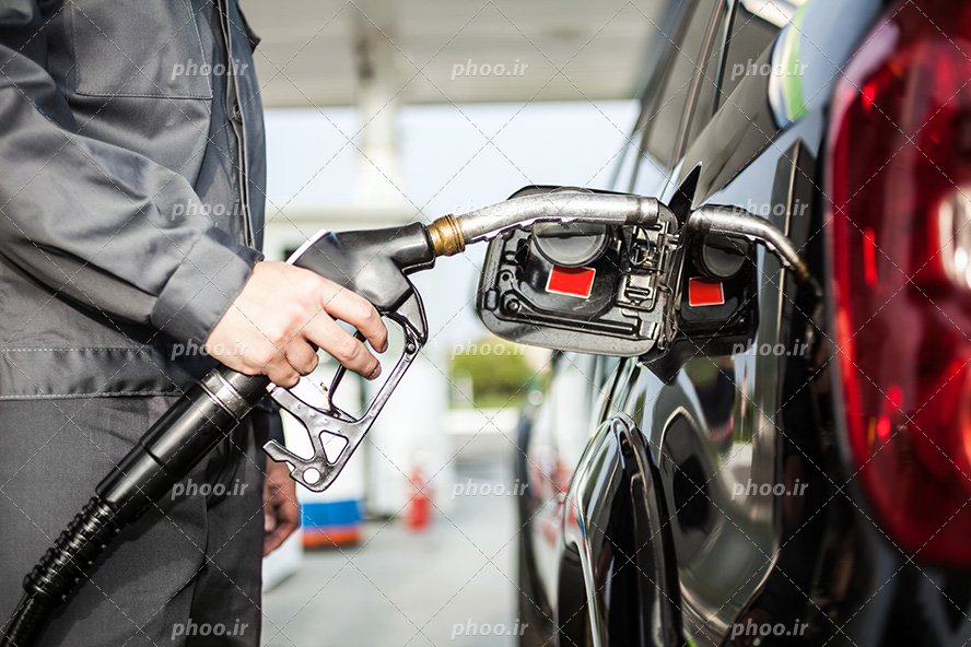 عکس با کیفیت مرد در حال استفاده و سوخت گیری از شیلنگ پمپ بنزین