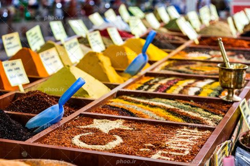 عکس با کیفیت قفسه های ادویه و گیاهان دارویی در کنار یکدیگر و در کنار آنها قفسه قهوه ترکی و در آن پرچم ترکیه و نوشته ترکیه با شیر خشک بر روی آن