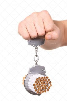 عکس با کیفیت دستبند در دست مرد و سیگار ها در دستبند به منظور اسیر شدن توسط دخانیات و مواد مخدر