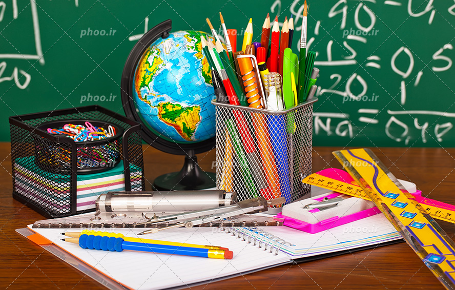 عکس با کیفیت خط کش ها و پرگار و مداد بر روی دفتر و دفتر در کنار جامدادی و جا کاغذی و کره زمین