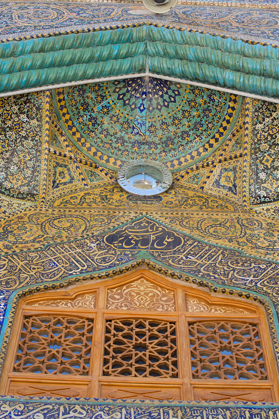عکس با کیفیت طرح یا پوستر حرم مطهر امام علی (ع) آینه ای محدب بر روی دیوار کاشی شده و پنجره چوبی کنده کاری شده با نقوش هندسی و تصویر حرم مطهر در آینه