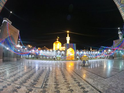 عکس با کیفیت طرح یا پوستر حرم مطهر امام رضا (ع) صحن زیبا با تزیین چراغ های رنگی و سقا خانه طلایی در وسط صحن و گنبد و گلدسته طلا در شب