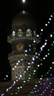 عکس با کیفیت طرح یا پوستر حرم مطهر امام رضا (ع) گلدسته ساعت حرم امام رضا و محل ایستادن نقاره زن ها و چراغ های رنگی در جلوی تصویر