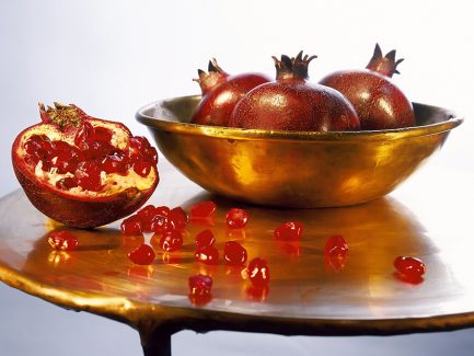 عکس با کیفیت طرح یا پوستر شب یلدا انار های زیبا در ظرف طلایی و بر روی میز طلایی و اسلایس انار و دانه های انار بر روی میز