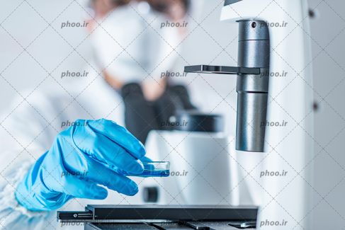 عکس با کیفیت پزشک در حال برسی و آزمایش و در حال استفاده از میکروسکوپ از نمای نزدیک