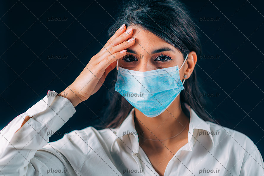 عکس با کیفیت زن با ماسک آبی و دست بر روی سر و پس زمینه به رنگ مشکی