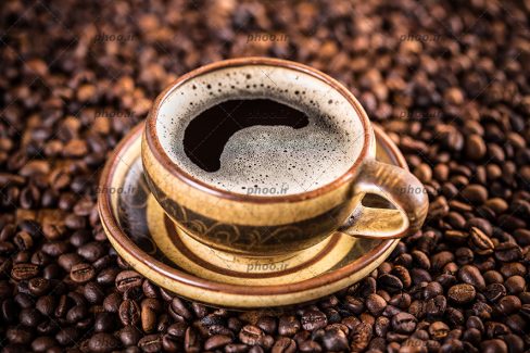 عکس با کیفیت فنجان قهوه قرار گرفته بر روی دانه های قهوه