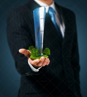 عکس با کیفیت ساختمان مرتفع در دست مرد با کت و شلوار مشکی و پس زمینه خاکستری در پشت او