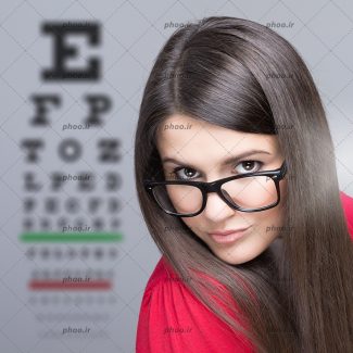 عکس با کیفیت زن با عینک مشکی و پیراهن قرمز و تست بینایی در کنارش