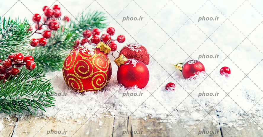 عکس با کیفیت توپ های قرمز رنگ مناسب برای تزئین درخت کاج و برف های در کنار آن ها