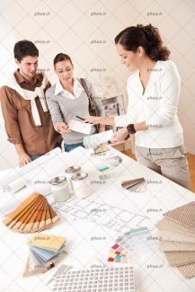 عکس با کیفیت زن در حال نشان دادن جدول ترکیب رنگ ها به زوج و جدول رنگ ها بر روی میز